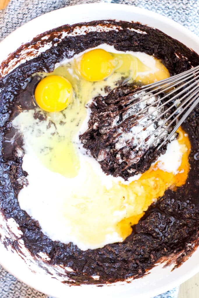 Adding eggs and milk to mocha cake batter